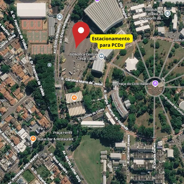 Mapa aéreo da Unicamp com destaque em vermelho indicando "Estacionamento para PCDs" localizado próximo à Biblioteca Central Cesar Lattes, com identificação de ruas adjacentes incluindo R. Carolina Maria de Jesus, Praça Henfil.